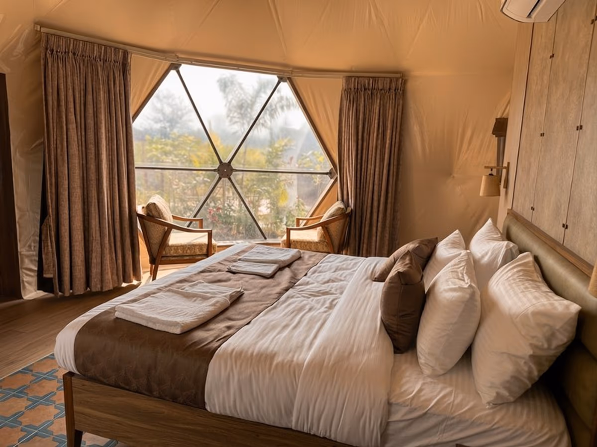 Garden Glade Getaways - king bed with geodesic window framing lush garden view