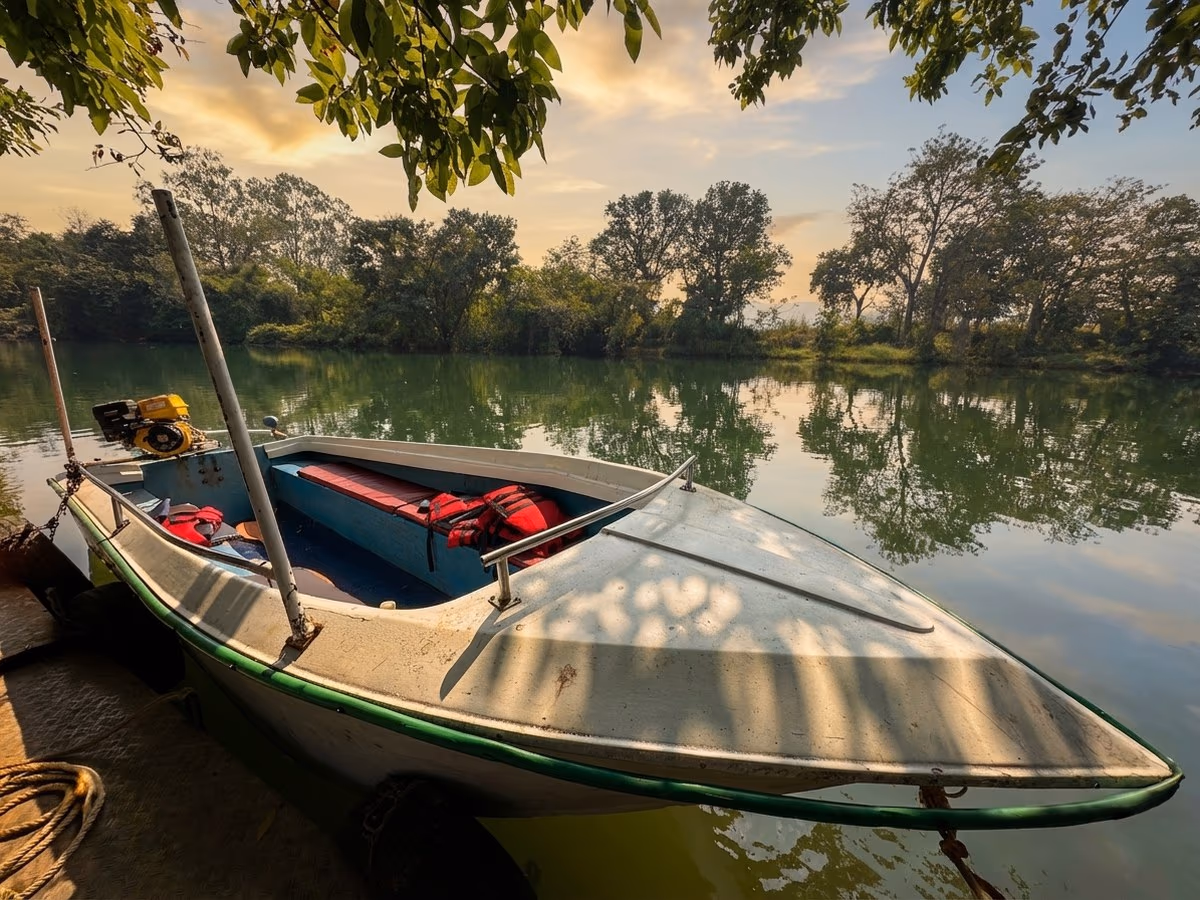 Motorboat moored on the calm Pavana river framed by tree canopy