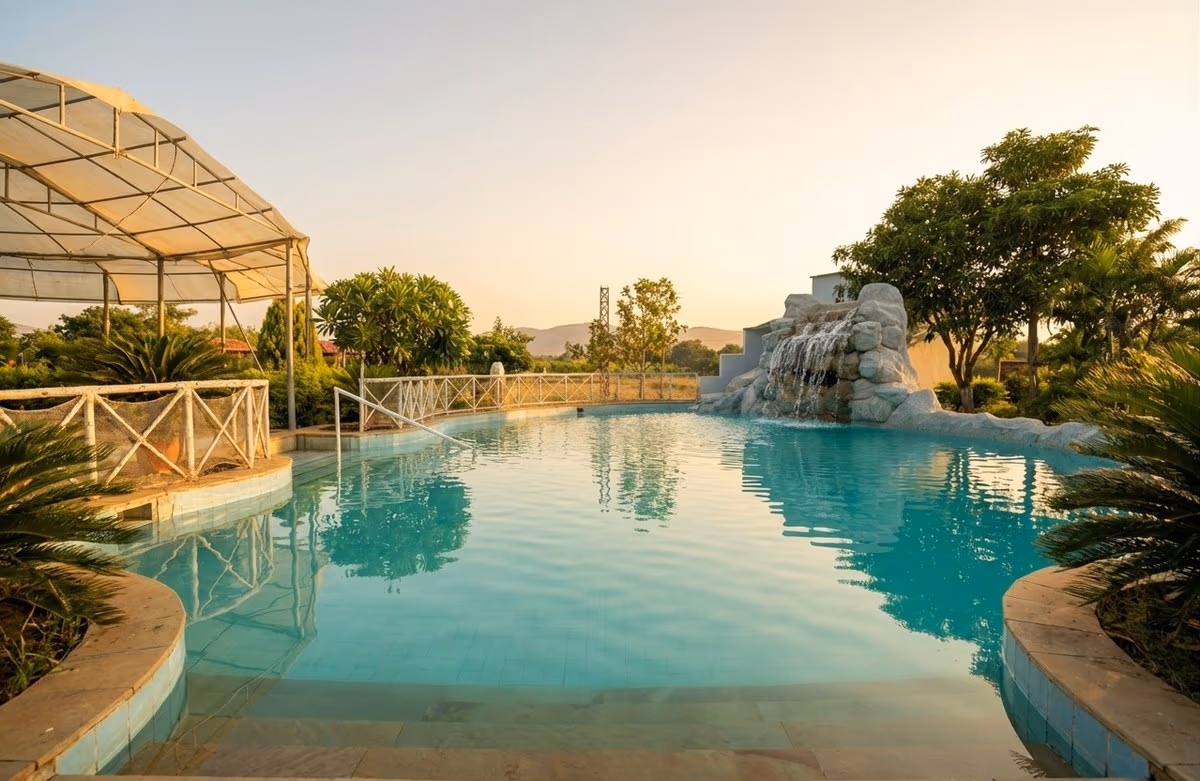Lagoon-style swimming pool with rock waterfall at golden hour