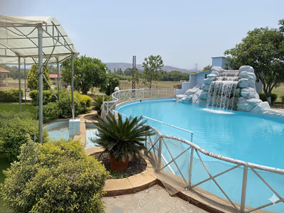 Lagoon-style swimming pool with rock waterfall at The Glen Woods Resort
